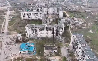O vedere aeriană a unor clădiri de apartamente multietajate cu fațade deteriorate și resturi împrăștiate pe terenul de lângă ele.
