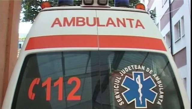 Partea din spate a unei ambulanțe albe prezintă inscripția AMBULANTA, numărul 112 și un simbol medical într-un cerc cu text.
