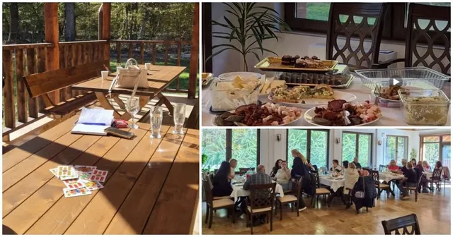 O masă de lemn cu pahare și obiecte, platouri cu mâncare și un grup de persoane așezate la mese într-o încăpere cu ferestre mari.