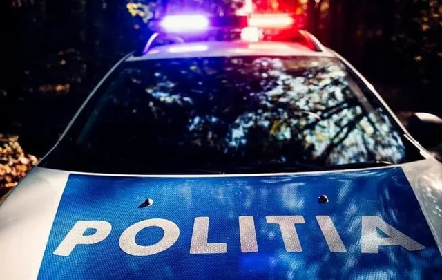 Un autovehicul de poliție cu girofaruri aprinse este surprins din față, având inscripția POLITIA pe capotă.