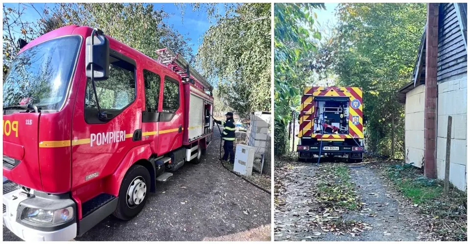 Un camion de pompieri roșu este parcat pe un drum, iar în partea dreaptă se vede spatele unui vehsil de intervenție galben și albastru.