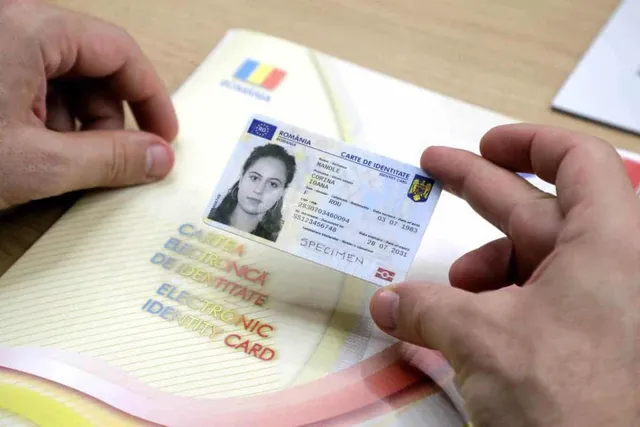 Două mâini țin un specimen de carte de identitate românească deasupra unui plic alb cu tricolorul României.
