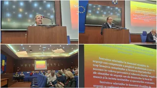 O femeie vorbește la un microfon de la un podium, în fața unui ecran mare, într-o sală de conferințe.