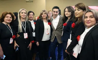 Un grup de persoane îmbrăcate în haine negre și albe stau grupate pentru o fotografie într-un spațiu interior.