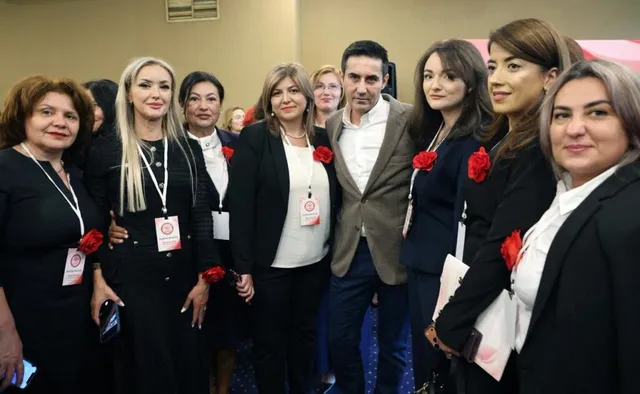 Un grup de persoane îmbrăcate în haine negre și albe stau grupate pentru o fotografie într-un spațiu interior.