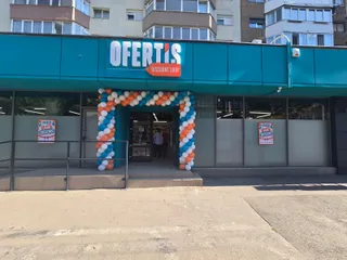 O clădire cu un panou albastru pe care scrie Ofertis Discount Shop este decorată cu un arc de baloane albe și albastre la intrare.