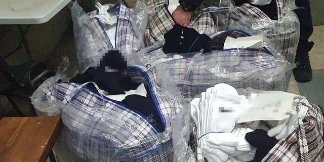 Mai multe pungi de plastic transparente conțin articole textile împachetate, printre care se observă obiecte albe și negre.