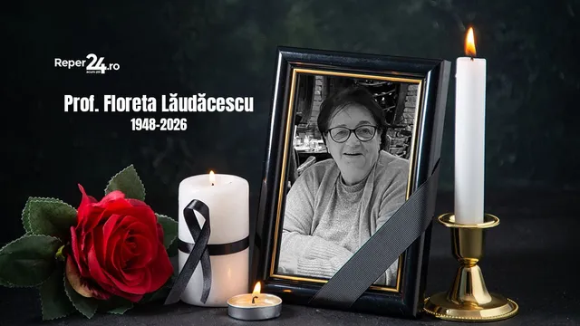 Un cadru cu o fotografie de portret a unei femei, alături de un trandafir roșu, două lumânări aprinse și o panglică neagră pe fundal întunecat.