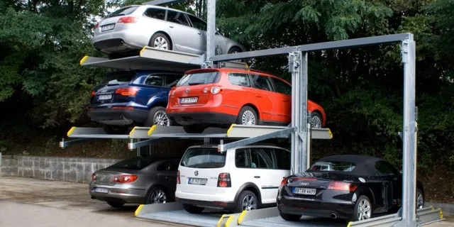 Mai multe mașini sunt parcate pe platforme metalice înaltă, într-un complex de parcare verticală din aer liber.
