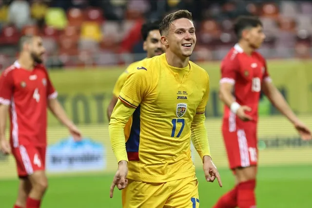 Un jucător de fotbal într-un echipament galben cu numărul 17 zâmbește pe un teren de fotbal, fiind înconjurat de alți jucători în echipamente roșii.