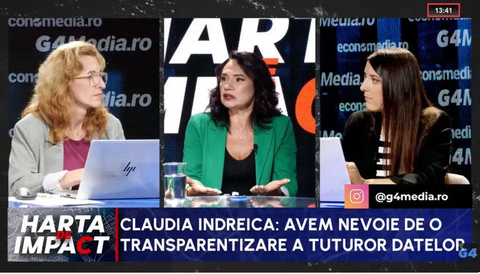 Trei femei stau la o masă într-un studio de televiziune, având un laptop și un pahar cu apă în față.