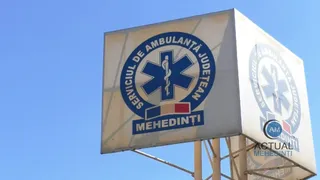 Un panou publicitar alb afișează un logou circular albastru cu simbolul Stația Vieții și textul Serviciul de Ambulanță Județean Mehedinți pe un fundal albastru.