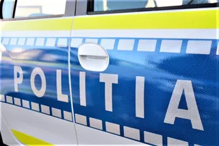Un detaliu al unei portiere de autoturism cu inscripția POLITIA pe un fundal albastru și galben.