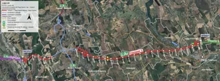 O hartă satelit cursivă prezintă un traseu de autostradă marcat cu linii roșii și secțiuni gri pe un peisaj rural cu câmpuri și păduri.