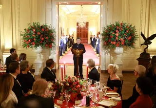 Donald Trump și Xi Jinping apar la o cină de stat într-un salon elegant, în fața unor mese cu floră și lumânări.