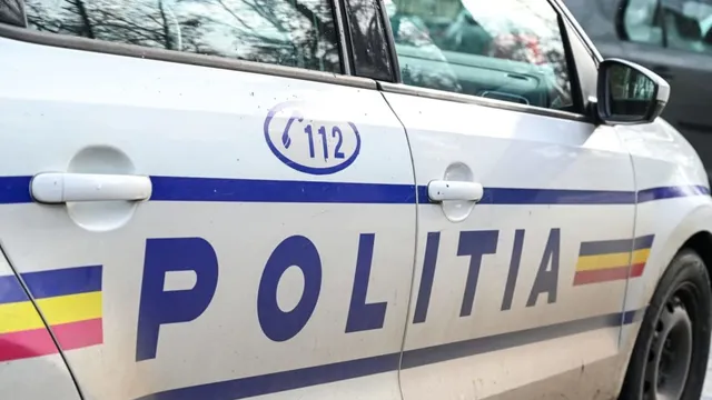 Un autovehicul alb prezintă inscripția POLITIA și simbolul numărului de urgență 112 pe portiera sa.