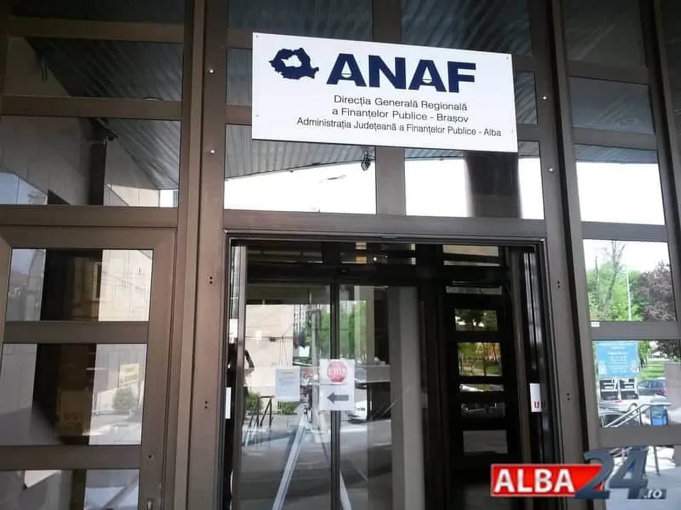 O intrare de sticlă cu un panou alb pe care scrie ANAF și alte detalii textuale, situată deasupra unei uși automate.