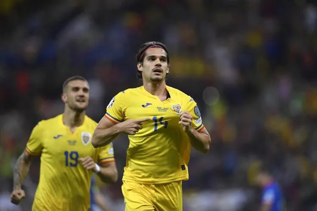 Un jucător de fotbal în echipament galben cu numărul 14 indică spre pieptul său, fiind urmat de un alt jucător în echipament similar.