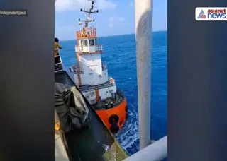 O navă mare de culoare albă și portocalie navighează pe o suprafață de apă albastră sub un cer înnorat.