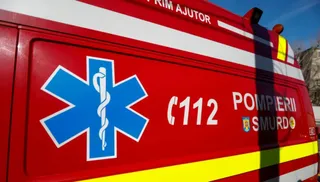 A close-up of a red Romanian emergency vehicle (Pompiers Smurd) showing the blue Star of Life emblem, the emergency number 112, and reflective stripes.