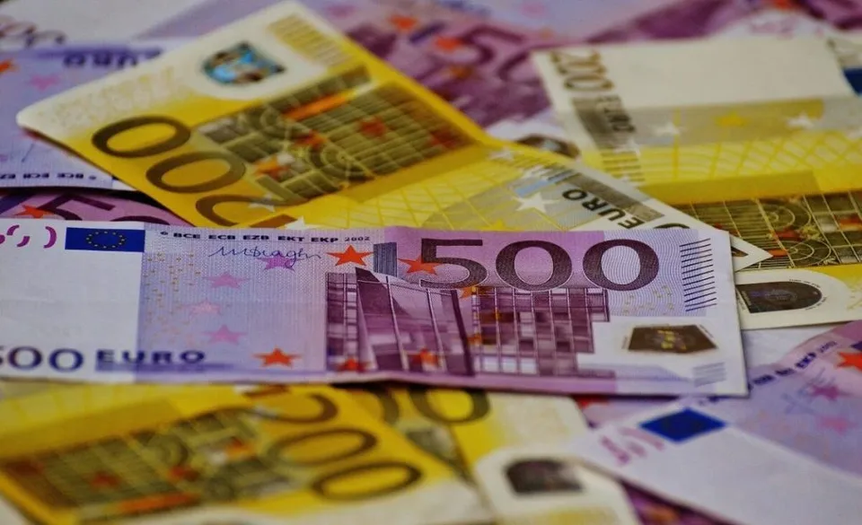 Mai multe bancnote de euro de diferite valori sunt împrăștiate pe o suprafață plană.