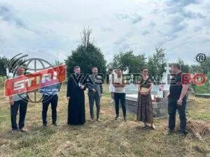 Un grup de persoane stă în picioare pe un teren cu iarbă sub un cer înnorat.
