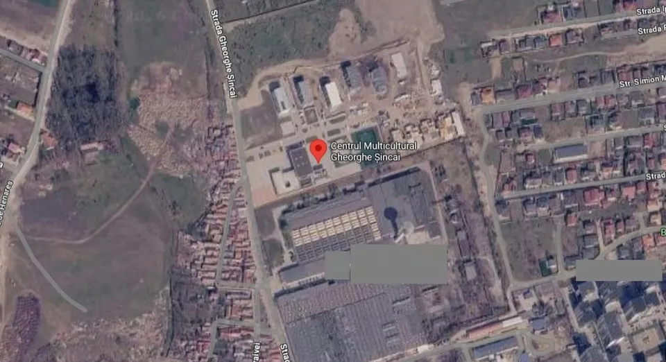 O imagine aeriană de satelit prezintă un ansamblu de clădiri, străzi și zone cu vegetație într-o zonă urbană.