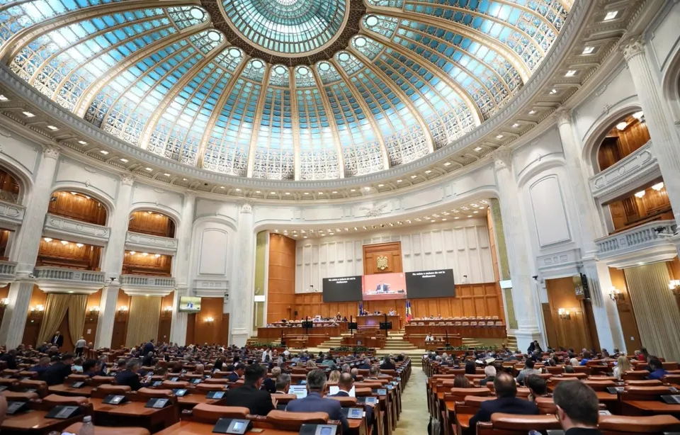 O sală circulară mare cu un dom de sticlă și oameni așezați la mese lungi în fața unei tribune centrale înălțate.