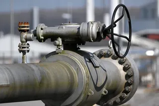 O conductă metalică mare este conectată la o valvă cu o roată de control neagră și diverse componente industriale de îmbinare.