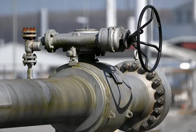 O conductă metalică mare este conectată la o valvă cu o roată de control neagră și diverse componente industriale de îmbinare.