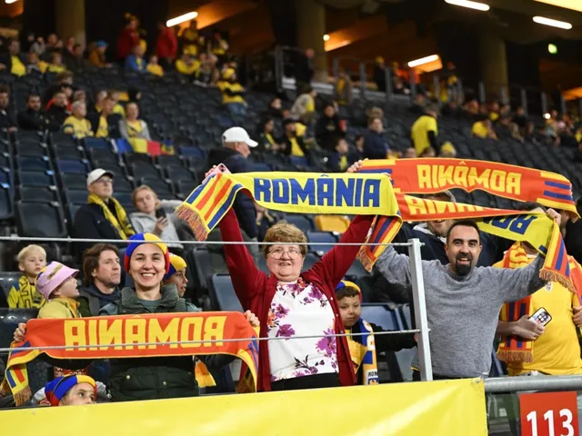 Oameni stau în tribunele unui stadion și ridică eșarfe colorate cu inscripții, printre care una cu textul ROMANIA.