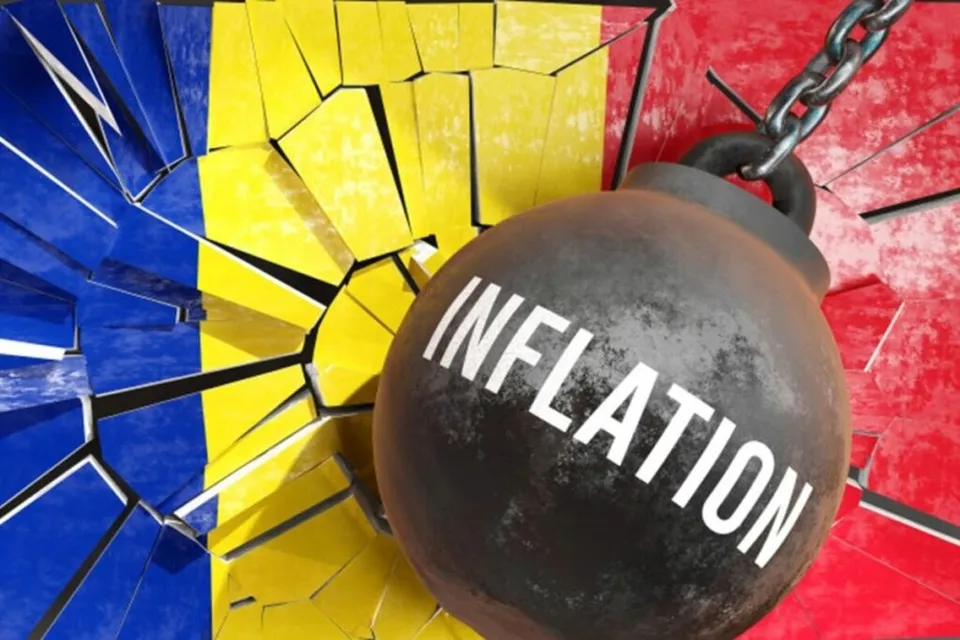 O bilă metalică neagră cu textul alb "INFLATION" este suspendată de un lanț în fața unui fundal colorat de albastru, galben și roșu fragmentat.