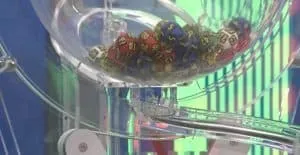 Numere rotunde, colorate, cu cifre albe, sunt grupate într-un recipient transparent de plastic.