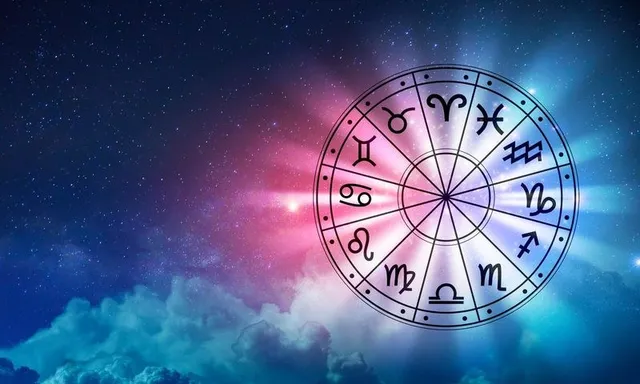 O roată astrologică cu semnele zodiacului pe un fundal cosmic cu stele și nori luminoși, în tonuri de albastru și roz.