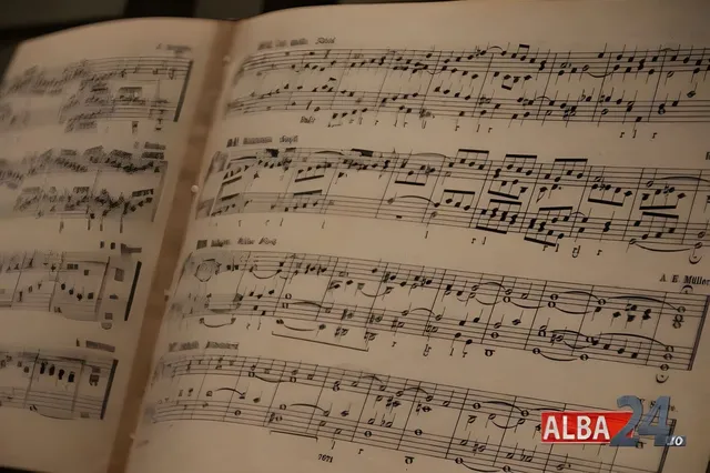 Pagini deschise ale unei partituri muzicale cu note scrise pe rânduri de pentagramă sub o lumină caldă.