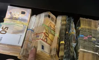 Mai multe teancuri de bancnote euro sunt grupate cu elastice pe o suprafață întunecată.