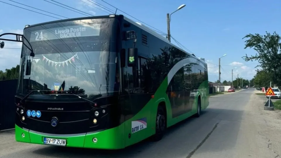 Un autobuz verde și negru cu numărul 24 afișat pe partea frontală circulă pe un drum asfaltat sub un cer senin.