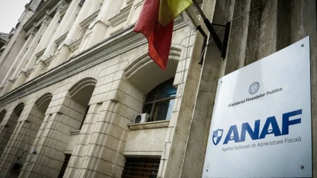 O clădire cu fațadă de piatră și arcade prezintă un panou alb cu siglul ANAF și un steag suspendat pe perete.