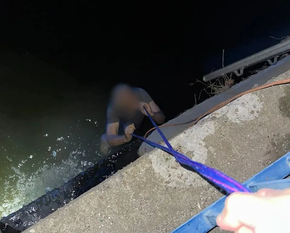 O persoană este trasă dintr-un corp de apă de pe un mal de beton folosind o sfoară albastră.