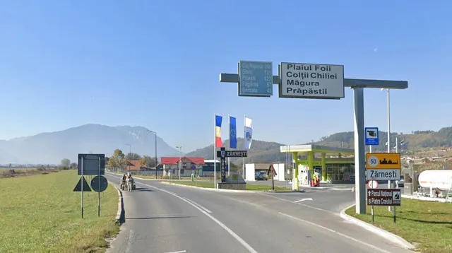 O șosele cu o bandă pe fiecare parte, un semafan de traseu la dreapta și un indicator de sens interzis la stânga, cu munți în fundal.