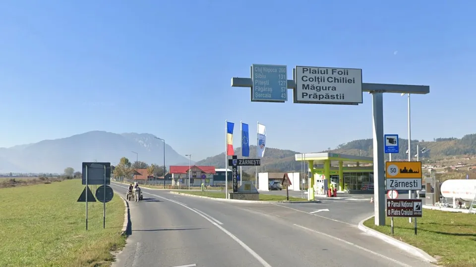 O șosele cu o bandă pe fiecare parte, un semafan de traseu la dreapta și un indicator de sens interzis la stânga, cu munți în fundal.
