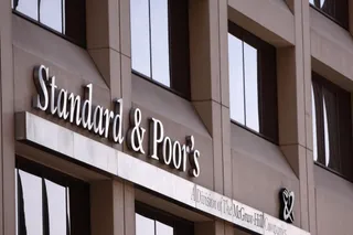 Un semn cu textul Standard & Poor's este montat pe fațada unei clădiri de birouri cu ferestre mari și negre.