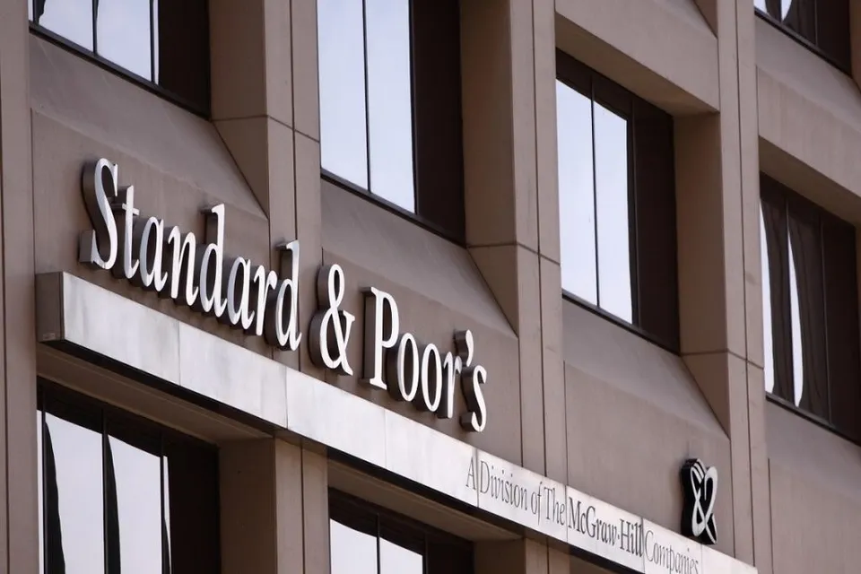 Un semn cu textul Standard & Poor's este montat pe fațada unei clădiri de birouri cu ferestre mari și negre.
