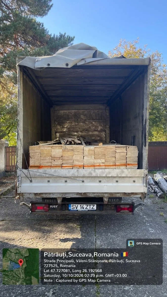 O autoutilitară albă cu spatele deschis este încărcată cu plăci de cherestea depozitate în interiorul compartimentului de marfă.
