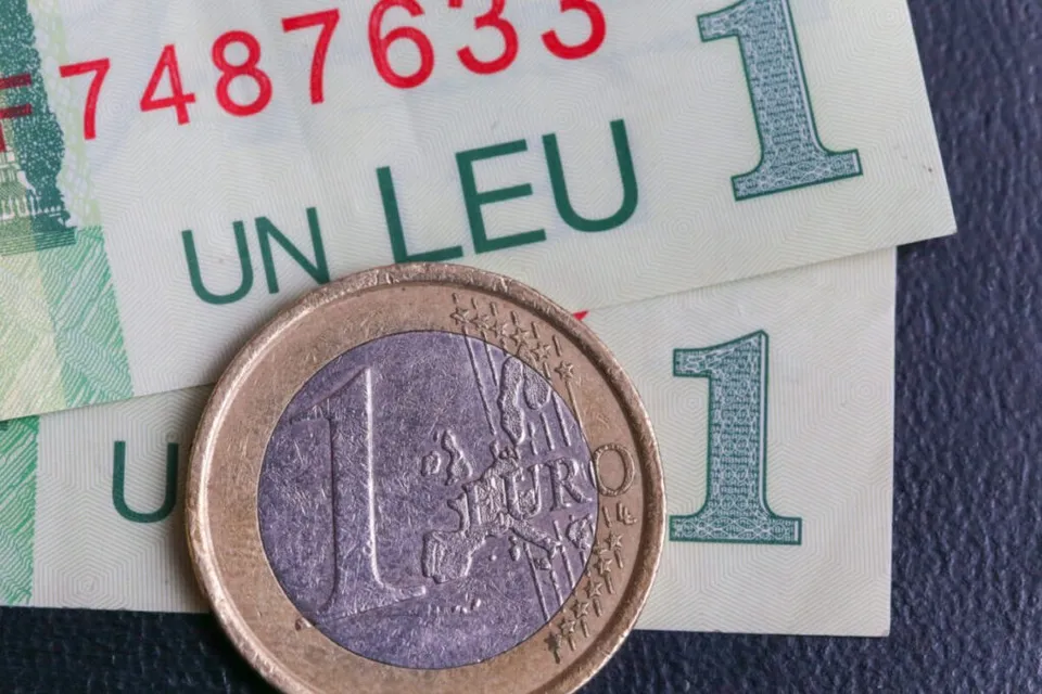 O monedă de un euro este așezată deasupra unor bancnote de un leu.
