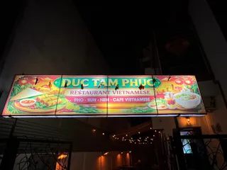 Un panou luminos afișează textul restaurantului vietnamez și diverse ilustrații cu mâncare și ingrediente pe un fundal colorat.