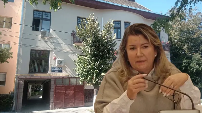 O femeie cu părul blond, purtând un pulover bej, ține ochelari în mâini în fața unei clădiri cu ferestre și vegetație.