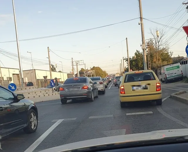 Mai multe autoturisme sunt implicate într-un rând de trafic pe un drum asfaltat, sub un cer senin.