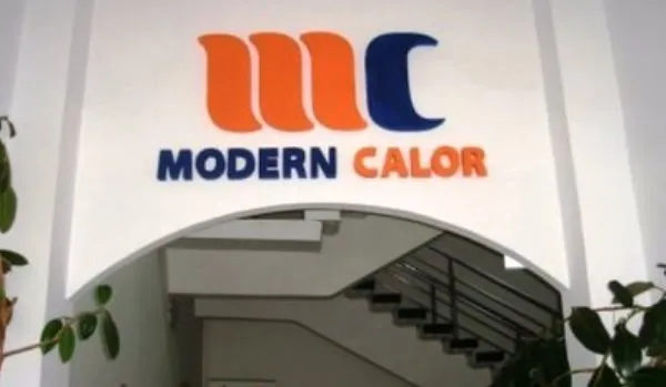 Un logo portocalii și albastru cu textul MODERN CALOR este montat pe un perete alb deasupra unei intrări cu scări interioare.