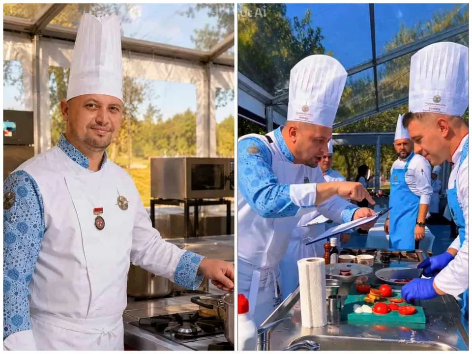 Un bărbat cu şapcă de bucătar albă și halat alb stă lângă un blat de bucătărie, în timp ce alți bărbați cu halate similare pregătesc mâncare.